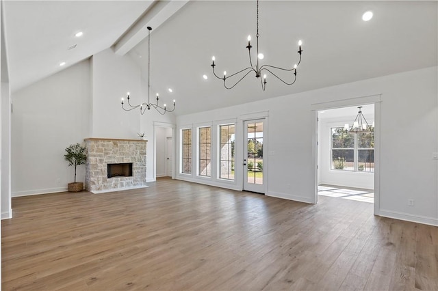 unfurnished living room featuring beam ceiling, a stone fireplace, high vaulted ceiling, and light hardwood / wood-style floors