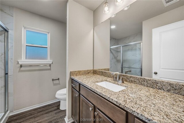 bathroom featuring vanity, wood-type flooring, a shower with door, and toilet