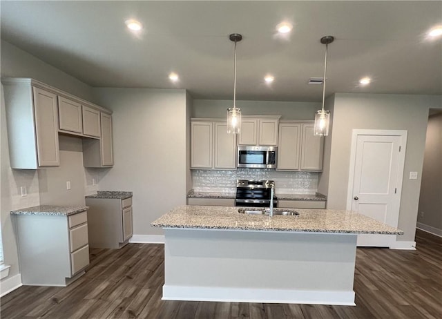 5307 Lyle Pl, Bryan, TX 77807 - kitchen with appliances with stainless steel finishes, dark wood-style floors, a kitchen island with sink, decorative backsplash, and light stone countertops