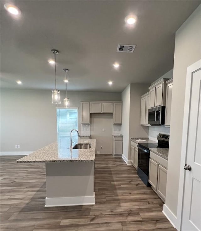 5307 Lyle Pl, Bryan, TX 77807 - kitchen with black electric range oven, stainless steel microwave, an island with sink, light stone counters, and dark wood-style flooring