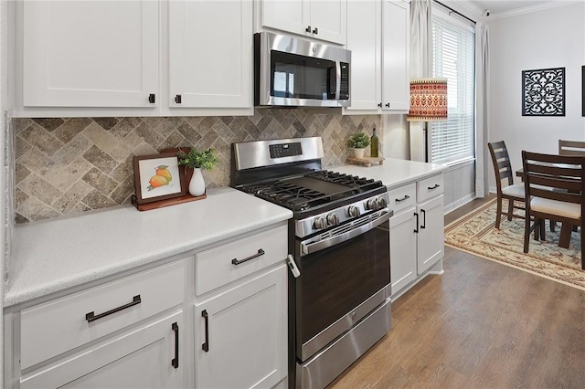 kitchen with white cabinetry, backsplash, light wood-type flooring, and appliances with stainless steel finishes