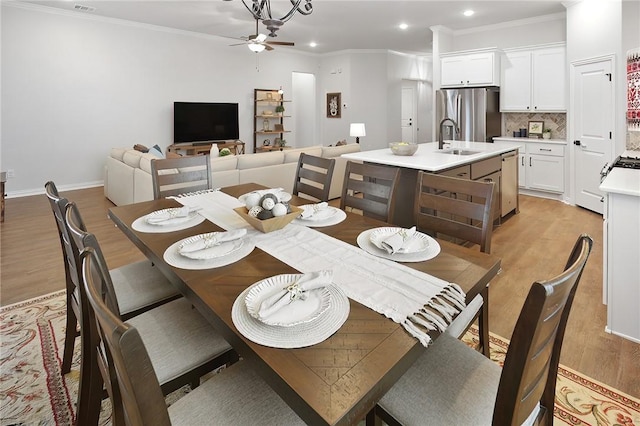 dining room with ornamental molding, sink, ceiling fan, and light hardwood / wood-style floors