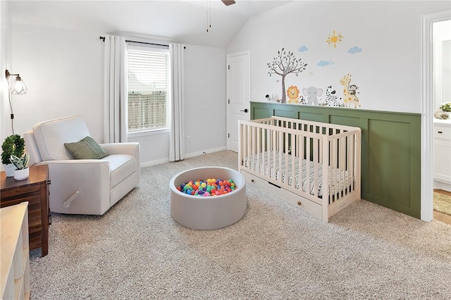 carpeted bedroom featuring vaulted ceiling and a nursery area