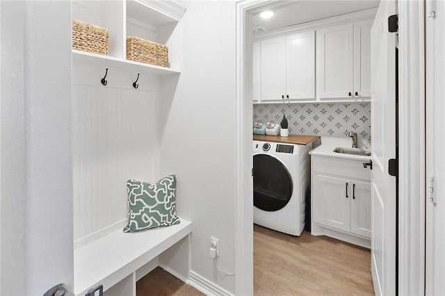 clothes washing area featuring washer / clothes dryer, sink, cabinets, and light wood-type flooring