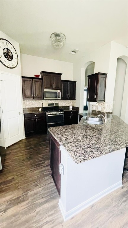 15481 Baker Meadow Loop, College Station, TX 77845 - kitchen with appliances with stainless steel finishes, arched walkways, a sink, and dark wood-style floors