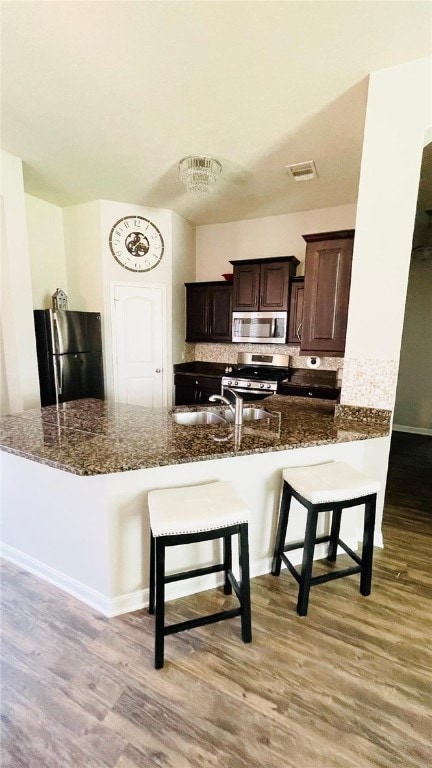 15481 Baker Meadow Loop, College Station, TX 77845 - kitchen with stainless steel appliances, light wood-style floors, a breakfast bar area, and dark stone counters