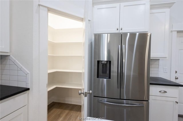 kitchen featuring hardwood / wood-style floors, decorative backsplash, stainless steel fridge, and white cabinetry