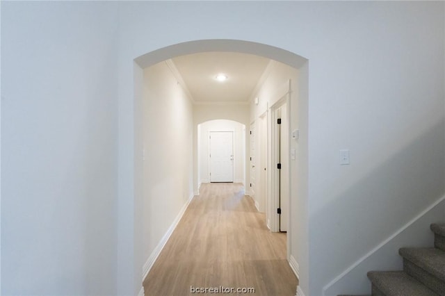 corridor with ornamental molding and light hardwood / wood-style flooring