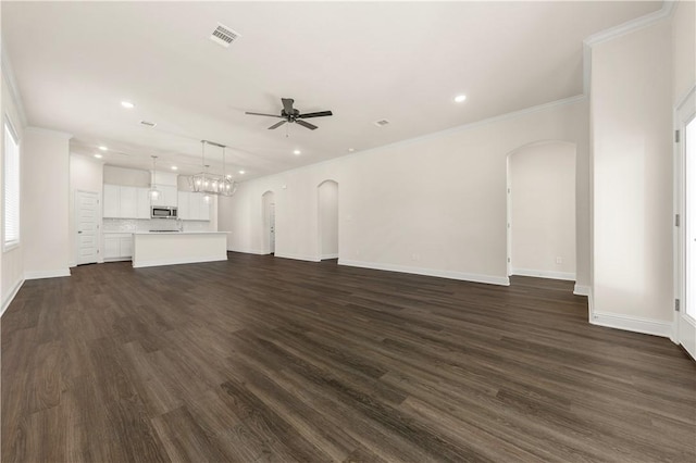 unfurnished living room featuring ceiling fan, crown molding, and dark wood-type flooring