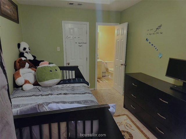 bedroom featuring connected bathroom and light carpet