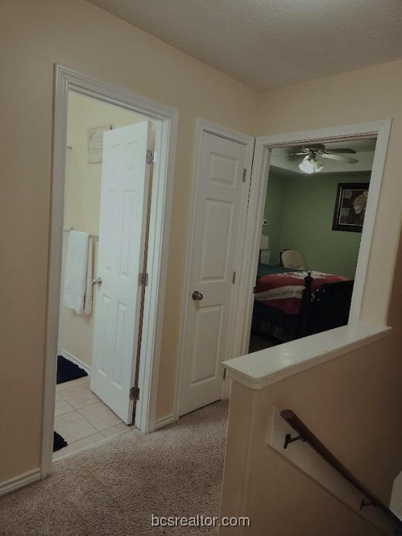 hallway featuring light colored carpet and a textured ceiling