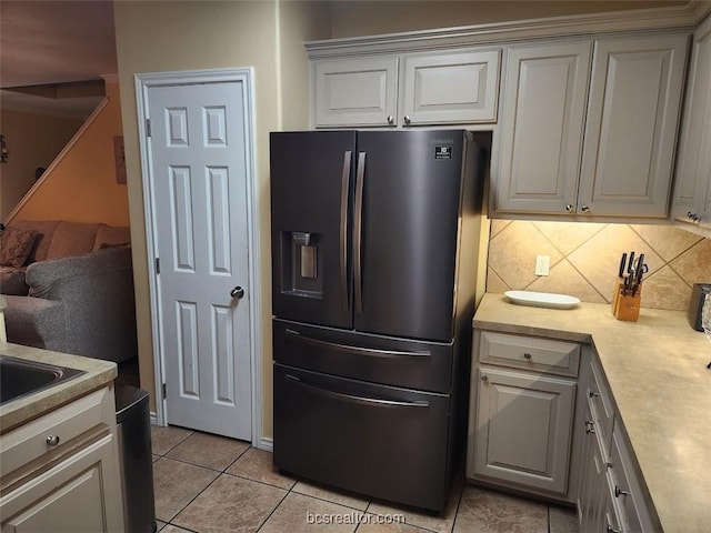 kitchen featuring white cabinets, stainless steel fridge, light tile patterned flooring, and backsplash