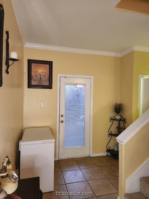 doorway to outside with ornamental molding and light tile patterned floors