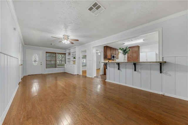 unfurnished living room with crown molding, hardwood / wood-style floors, ceiling fan, and a textured ceiling