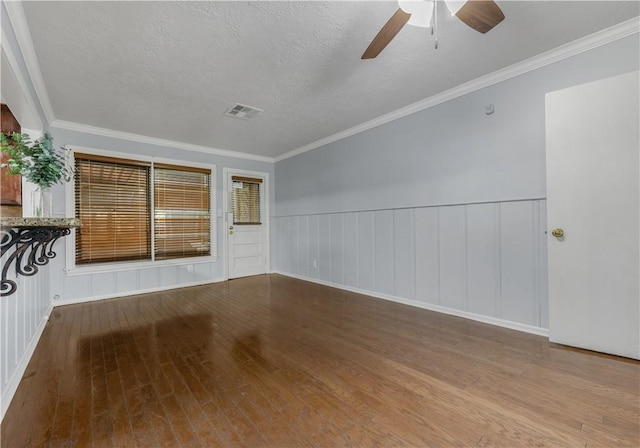 empty room with ceiling fan, wood-type flooring, a textured ceiling, and ornamental molding