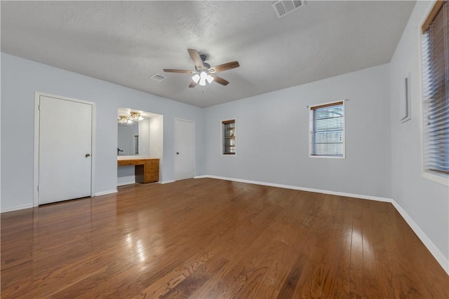 interior space with wood-type flooring, built in desk, a textured ceiling, and ceiling fan