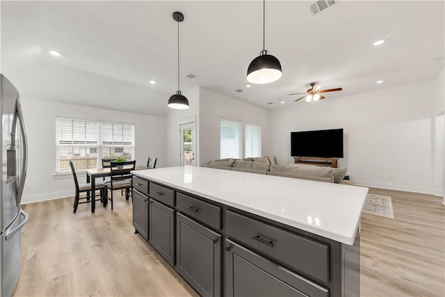 kitchen with ceiling fan, stainless steel fridge, light countertops, baseboards, and visible vents