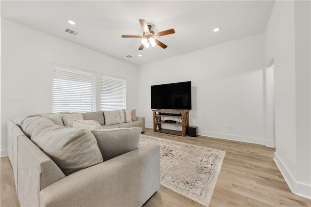 living area featuring visible vents, baseboards, ceiling fan, and light wood finished floors