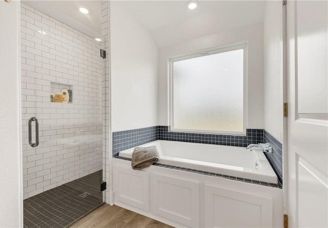 bathroom featuring wood finished floors, lofted ceiling, recessed lighting, a bath, and a shower stall