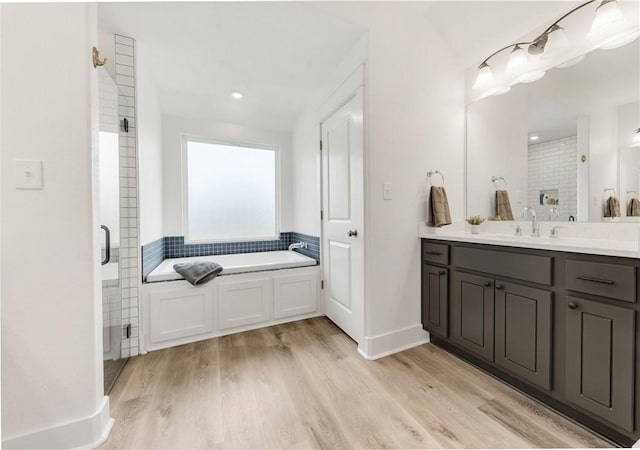 bathroom with vanity, a shower stall, wood finished floors, and a garden tub