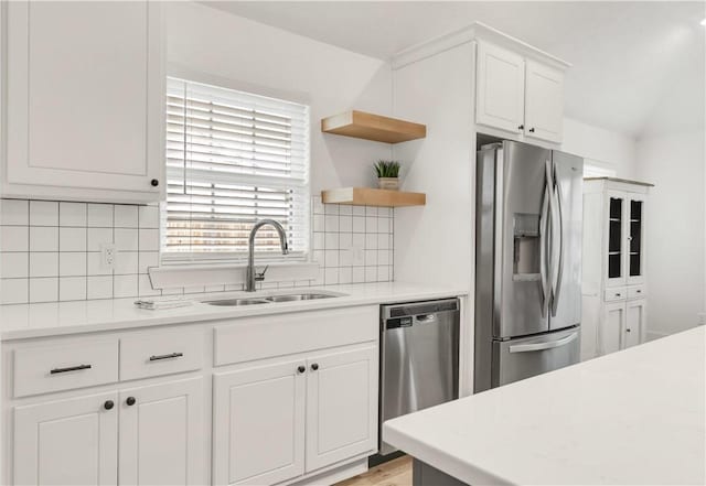 kitchen with light countertops, stainless steel appliances, decorative backsplash, and a sink