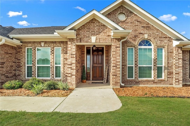 10008 Henley Cv, Iola, TX 77861 - doorway to property with brick siding, a lawn, and roof with shingles