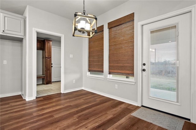 10008 Henley Cv, Iola, TX 77861 - unfurnished dining area featuring a chandelier, dark wood-type flooring, and baseboards
