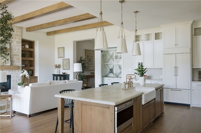 kitchen featuring white cabinetry, sink, dark wood-type flooring, paneled refrigerator, and an island with sink