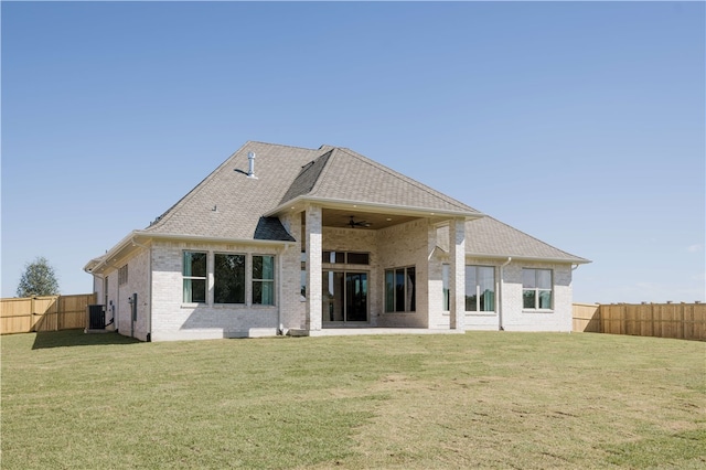 back of property with ceiling fan, a yard, and cooling unit