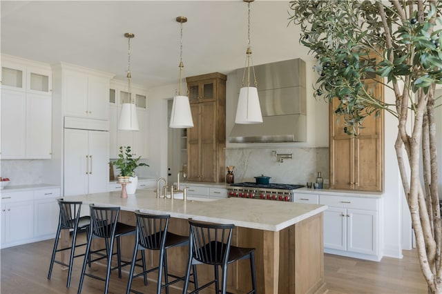 kitchen featuring hardwood / wood-style floors, a large island, white cabinetry, and wall chimney range hood