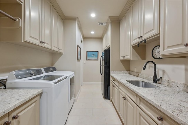 5205 Bourrone Ct, Bryan, TX 77802 - laundry room featuring washer and dryer, baseboards, light tile patterned floors, ornamental molding, and cabinet space