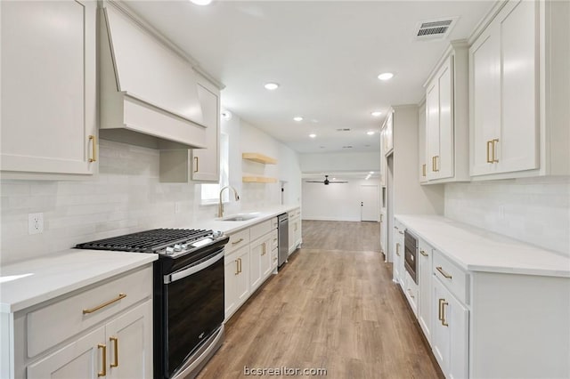 kitchen featuring white cabinetry, sink, ceiling fan, stainless steel appliances, and light wood-type flooring