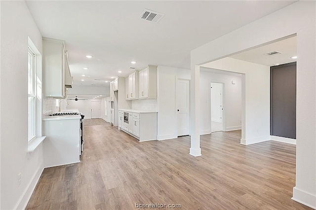 kitchen featuring white cabinets, tasteful backsplash, sink, and light hardwood / wood-style flooring