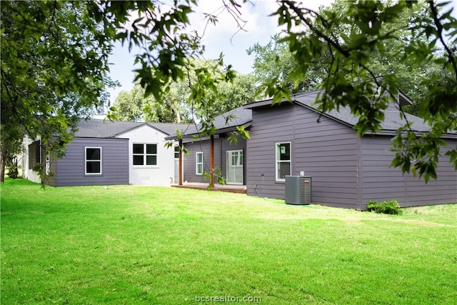 back of property featuring central air condition unit and a yard