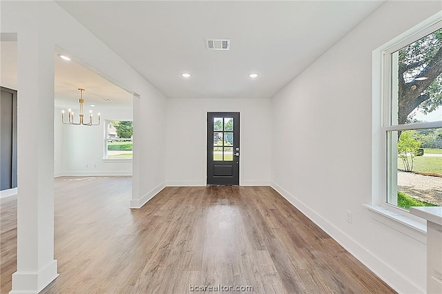 foyer entrance featuring a chandelier, light wood-type flooring, and plenty of natural light