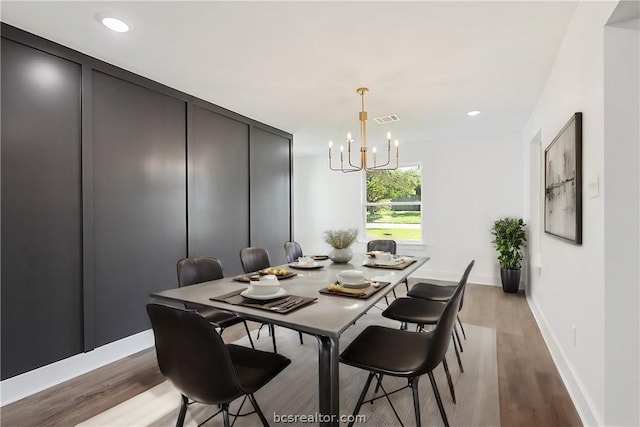 dining space with light hardwood / wood-style floors and a notable chandelier