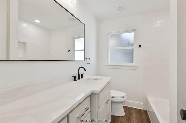 full bathroom featuring washtub / shower combination, wood-type flooring, vanity, and toilet