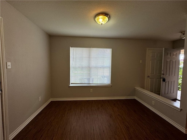 empty room featuring dark wood-type flooring and a textured ceiling