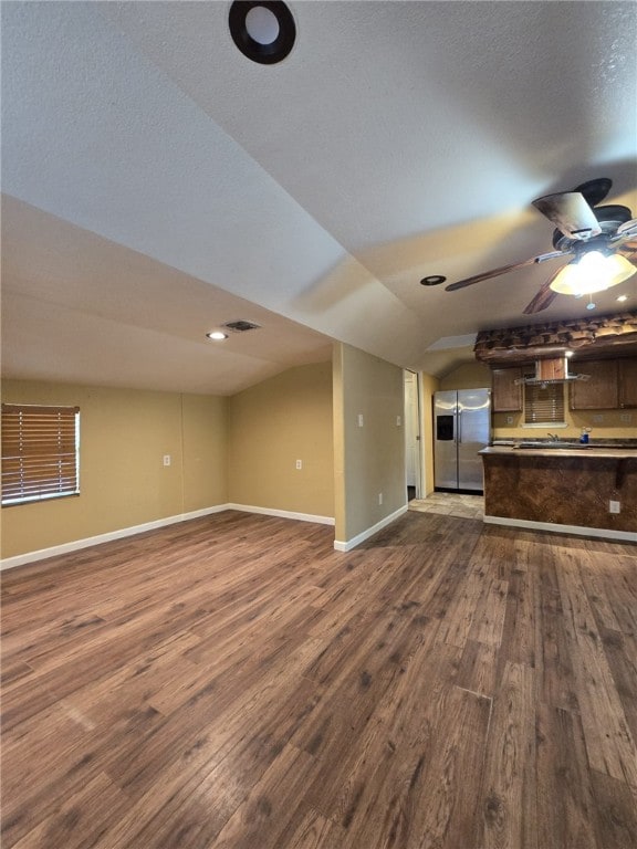 unfurnished living room with dark hardwood / wood-style floors, ceiling fan, and vaulted ceiling