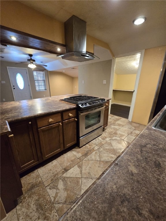 kitchen with sink, stainless steel gas stove, ceiling fan, dark brown cabinets, and island exhaust hood