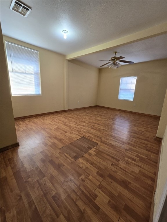 empty room featuring a wealth of natural light, hardwood / wood-style floors, ceiling fan, and a textured ceiling