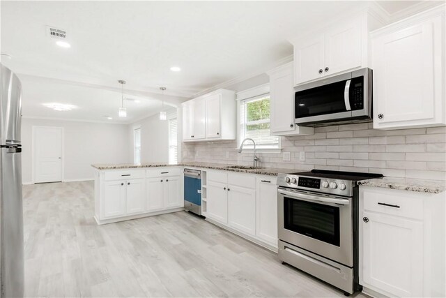 301 S Hutchins St, Bryan, TX 77803 - kitchen featuring appliances with stainless steel finishes, a sink, a peninsula, backsplash, and white cabinetry