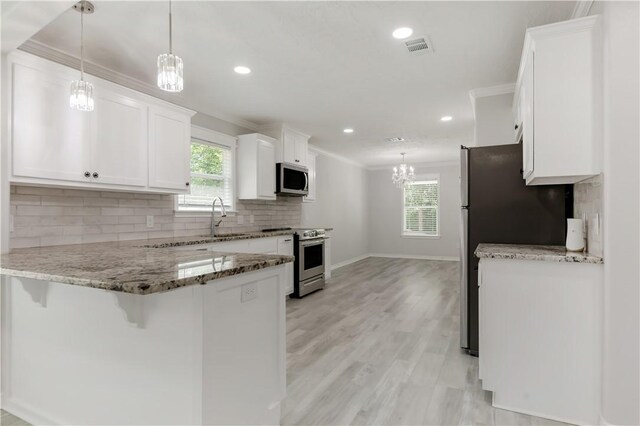 301 S Hutchins St, Bryan, TX 77803 - kitchen featuring appliances with stainless steel finishes, crown molding, light stone countertops, white cabinets, and a peninsula