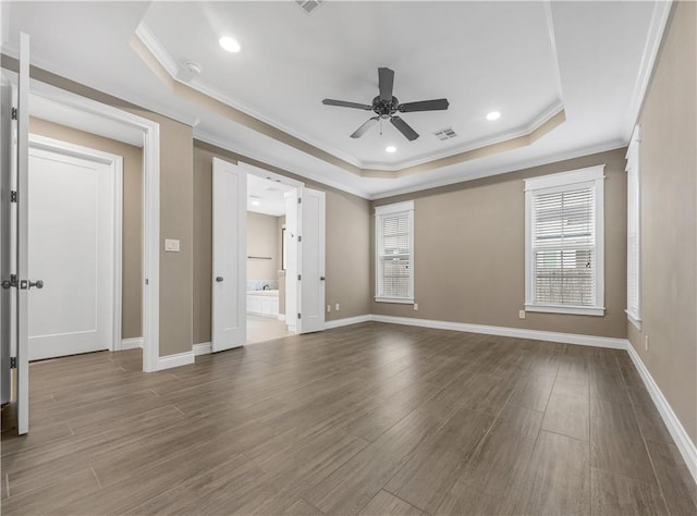 empty room with ceiling fan, wood-type flooring, ornamental molding, and a tray ceiling