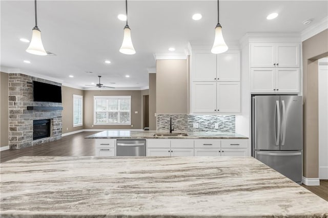 kitchen featuring white cabinets, pendant lighting, stainless steel appliances, and a fireplace