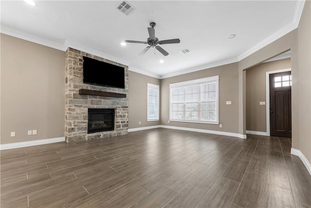 unfurnished living room featuring a stone fireplace, ceiling fan, dark hardwood / wood-style flooring, and a healthy amount of sunlight