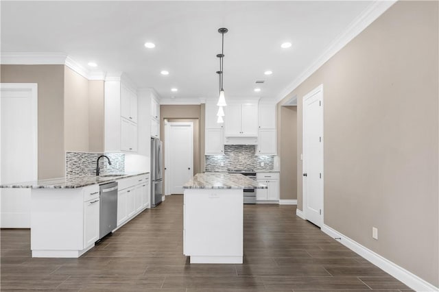 kitchen with white cabinets, decorative light fixtures, a center island, and stainless steel appliances