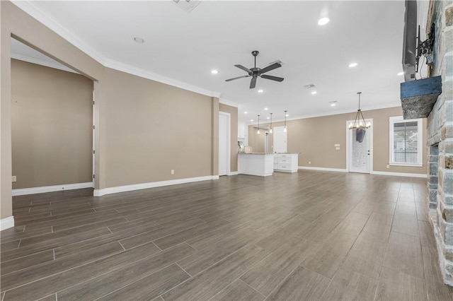 unfurnished living room featuring ceiling fan with notable chandelier, dark hardwood / wood-style flooring, ornamental molding, and a fireplace