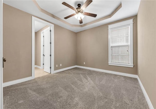 carpeted empty room featuring ceiling fan and a tray ceiling