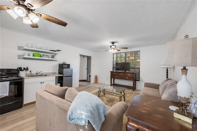 living room featuring light hardwood / wood-style flooring, ceiling fan, and sink